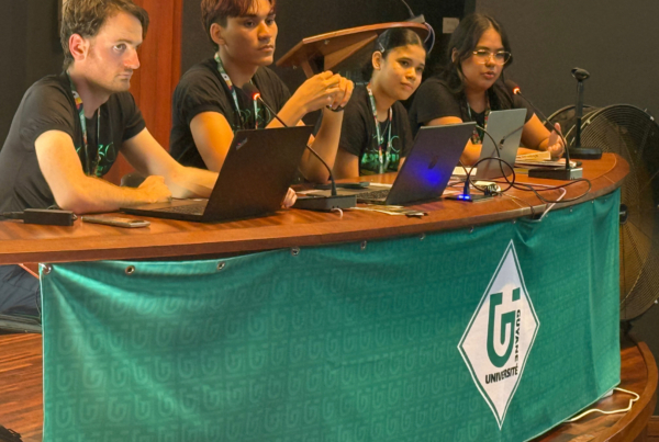 Quatre étudiants de l’Université de Guyane participent à une table ronde, assis derrière une table avec microphones et ordinateurs, lors d’un événement académique.