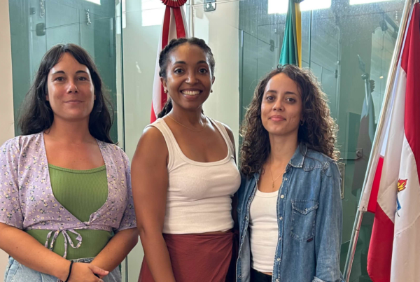 Les trois lauréates de l’Université de Guyane posent devant plusieurs drapeaux lors de leur mobilité au Pará, organisée dans le cadre d’une école immersive consacrée à la bioéconomie.