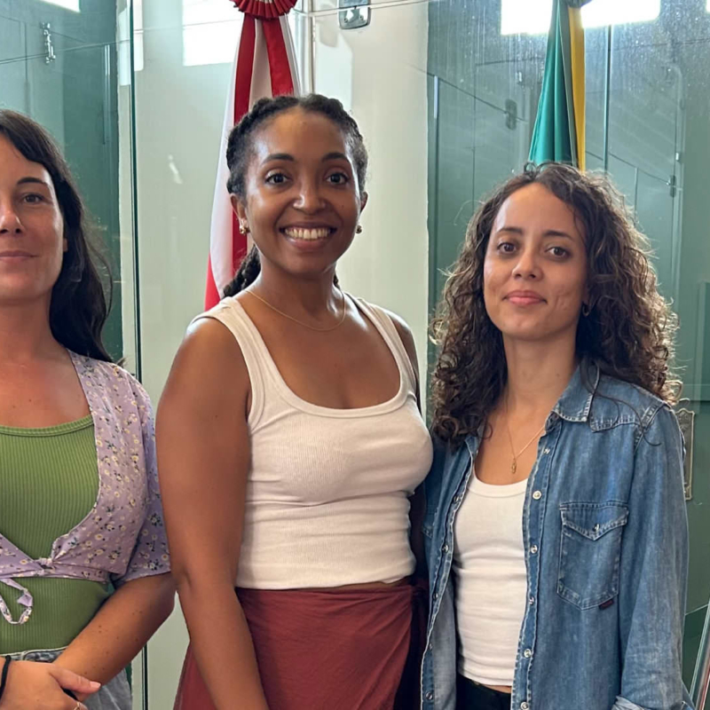 Les trois lauréates de l’Université de Guyane posent devant plusieurs drapeaux lors de leur mobilité au Pará, organisée dans le cadre d’une école immersive consacrée à la bioéconomie.