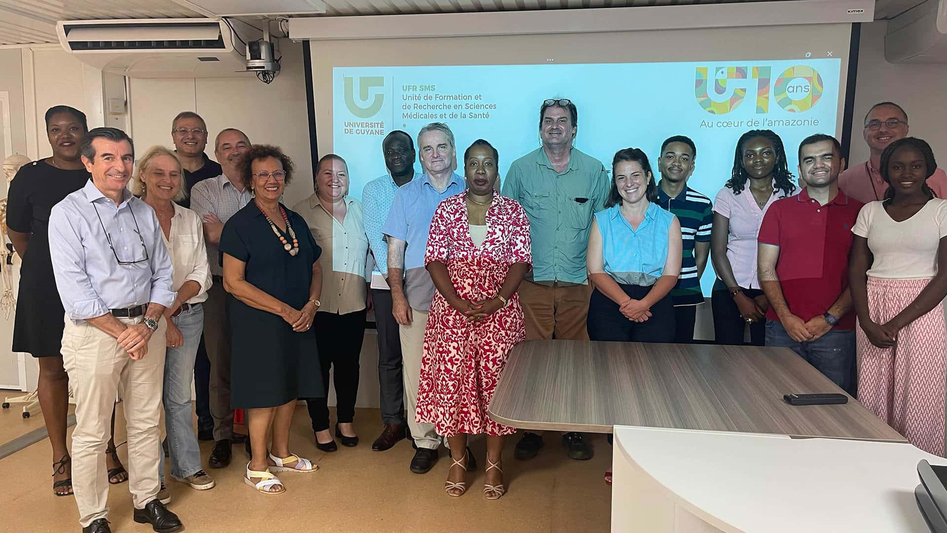Photo de groupe lors de l’élection du premier doyen de la Faculté des Sciences Médicales et de la Santé à l’Université de Guyane, avec les membres du conseil de l’UFR réunis devant un écran de présentation.