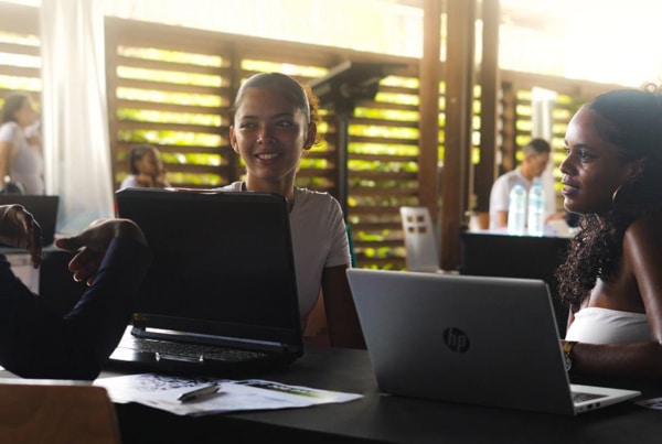 Trois jeunes adultes échangent avec des recruteurs lors du Job Dating de l’Université de Guyane 2025, assis autour d’une table avec leurs ordinateurs portables, dans une ambiance conviviale et professionnelle.