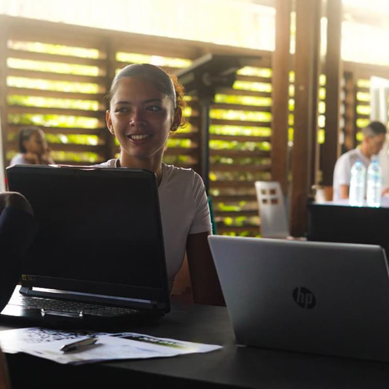 Trois jeunes adultes échangent avec des recruteurs lors du Job Dating de l’Université de Guyane 2025, assis autour d’une table avec leurs ordinateurs portables, dans une ambiance conviviale et professionnelle.
