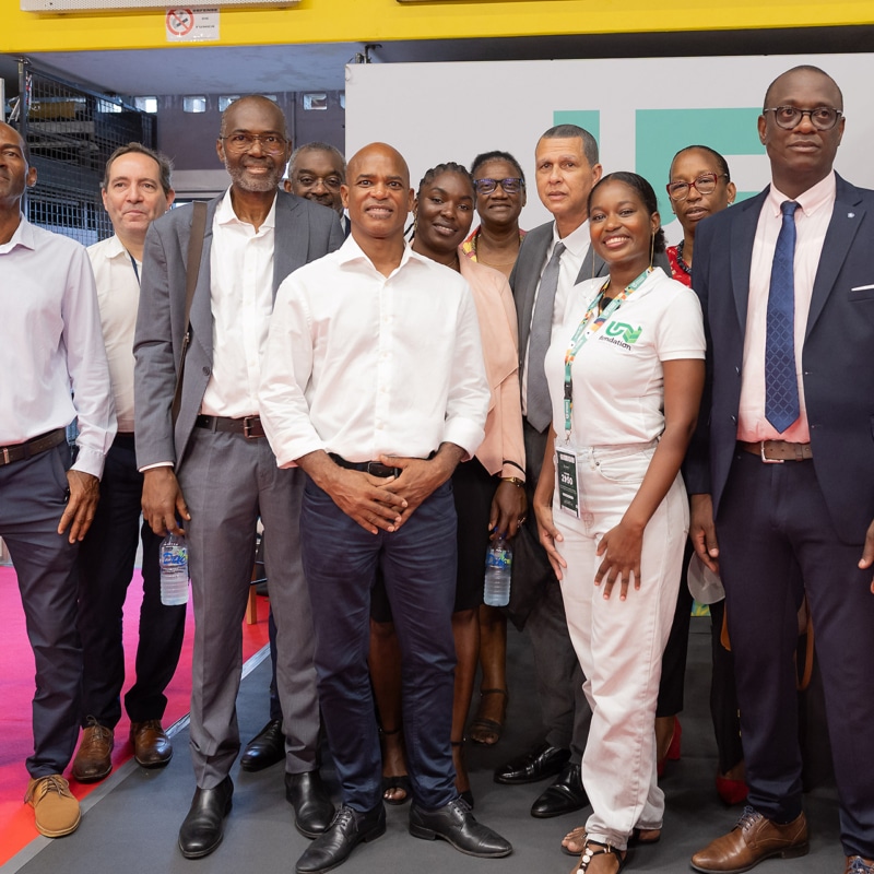 Lors du Salon des Maires à l’Université de Guyane, une délégation de l’université pose devant son stand, entourée de représentants et partenaires locaux. On aperçoit le logo « UG » (Université de Guyane) en arrière-plan, ainsi que des éléments de communication liés aux métiers et initiatives universitaires locales. Cette image illustre la participation institutionnelle, les échanges entre acteurs publics et universitaires, et l’implication de l’Université de Guyane dans le développement territorial.