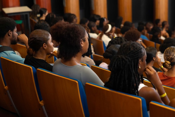 Étudiant·es et primo-arrivants assis dans un amphithéâtre, de dos, attentifs aux discours lors de la rentrée universitaire à l’Université de Guyane.