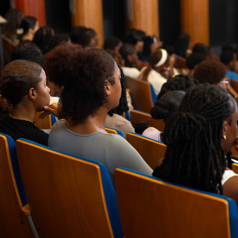 Étudiant·es et primo-arrivants assis dans un amphithéâtre, de dos, attentifs aux discours lors de la rentrée universitaire à l’Université de Guyane.