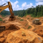 Vue photoréaliste d’un site minier aurifère en Guyane française, entouré de forêt tropicale. Au premier plan, un gros plan sur une pépite d’or posée sur une roche, avec une pelleteuse jaune en action et une structure industrielle à l’arrière-plan. L’image illustre l’exploitation responsable des ressources naturelles dans un cadre amazonien.